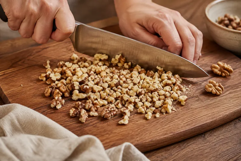 Geroosterde walnoten worden op een houten plank grof gehakt