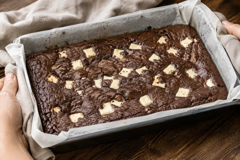 Versgebakken donkere brownieplaat met witte chocoladestukken in het korstje