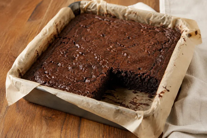 Gebakken brownie zonder ei koelt af in een met bakpapier beklede vorm