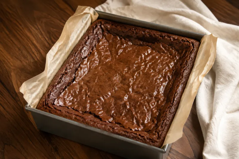 Gebakken chewy brownieplaat met stevige opstaande randen en een gekreukt midden