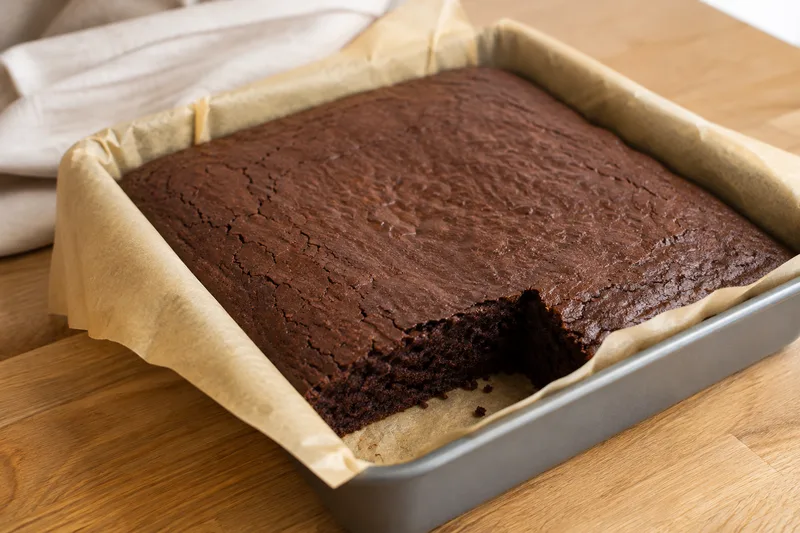 Glutenvrije brownie met een fijne vochtige kruim koelt af in de bakvorm